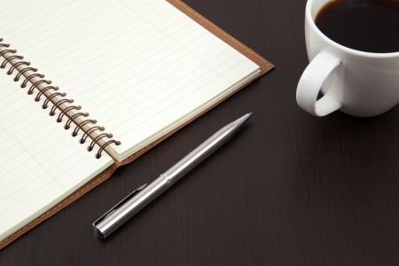 Cup of coffee on a wooden table with book and penの写真素材