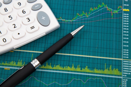 A pen and calculator on the Stock chart and financial reportの写真素材