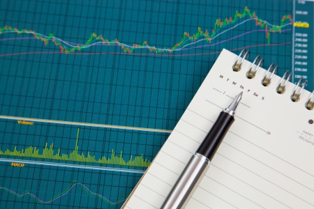A pen and notepad on the Stock chart and financial reportの写真素材