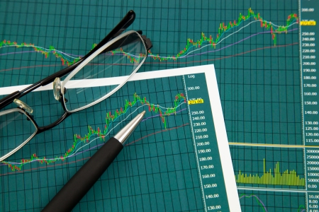 A pen and spectacles on the Stock chart and financial reportの写真素材