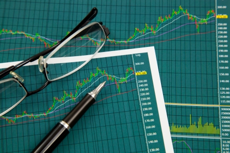 A pen and spectacles on the Stock chart and financial reportの写真素材
