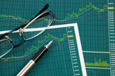 A pen and spectacles on the Stock chart and financial reportの写真素材
