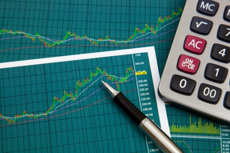 A pen and calculator on the Stock chart and financial reportの写真素材