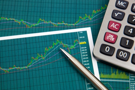 A pen and calculator on the Stock chart and financial reportの写真素材