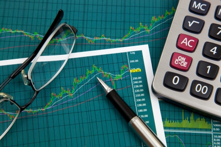 A pen, calculator and spectacles on the Stock chart and financial reportの写真素材