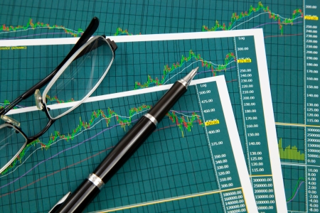 A pen and spectacles on the Stock chart and financial reportの写真素材