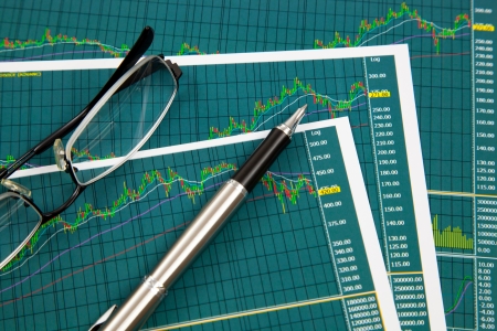 A pen and spectacles on the Stock chart and financial reportの写真素材