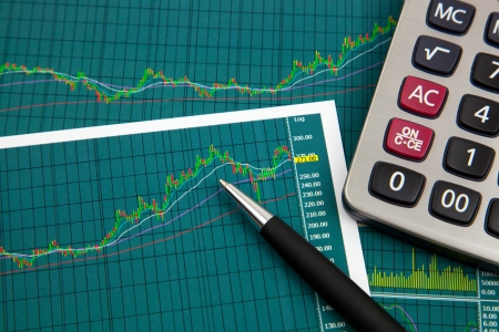 A pen and calculator on the Stock chart and financial reportの写真素材