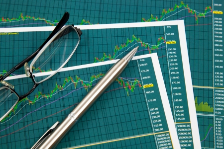 A pen and spectacles on the Stock chart and financial reportの写真素材