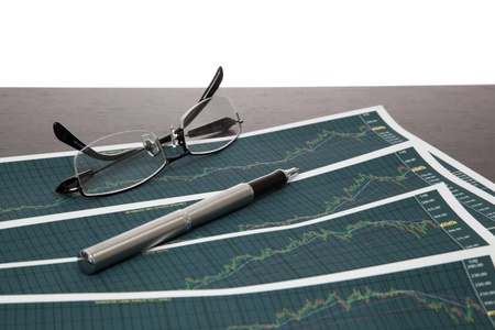 A pen and spectacles on the Stock chart and financial reportの写真素材
