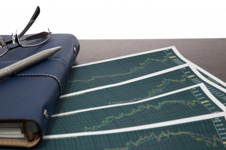 A pen and spectacles on the Stock chart and financial reportの写真素材