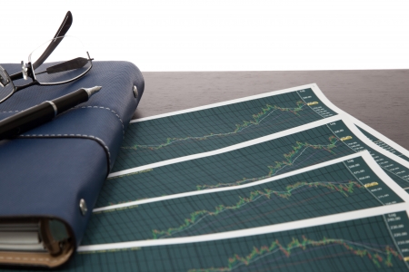 A pen and spectacles on the Stock chart and financial reportの写真素材