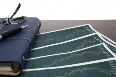 A pen and spectacles on the Stock chart and financial reportの写真素材