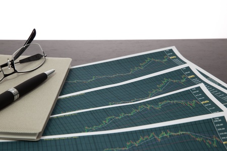 A pen and spectacles on the Stock chart and financial reportの写真素材