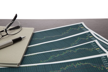 A pen and spectacles on the Stock chart and financial reportの写真素材
