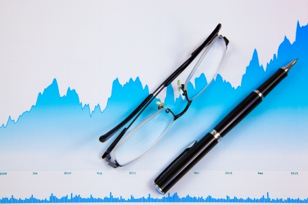 A pen and spectacles on the Stock chart and financial reportの写真素材