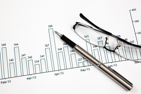 A pen and spectacles on the Stock chart and financial reportの写真素材