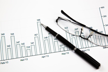 A pen and spectacles on the Stock chart and financial reportの写真素材