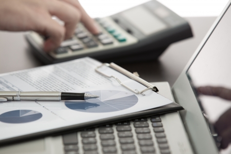 Businessman analyzing investment charts with laptopの写真素材