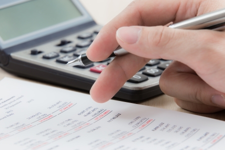 Finger is pressing calculator button on chartの写真素材
