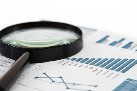 magnifying glass and pen over graph on tableの写真素材