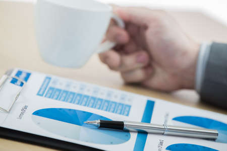 graphs and charts analyzed by businessman with coffeeの写真素材