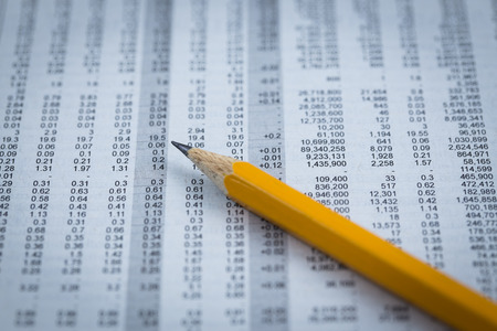 Pencil resting on world currency figuresの写真素材