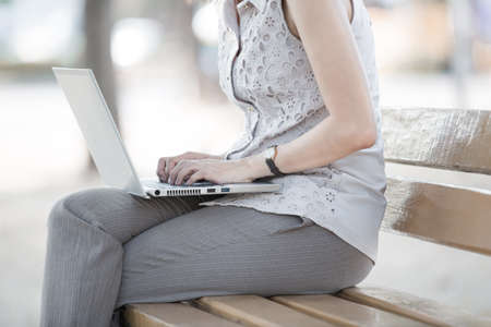 Portrait of a smiling young business woman using laptop on chairの写真素材