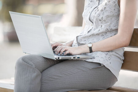 Portrait of a smiling young business woman using laptop on chairの写真素材