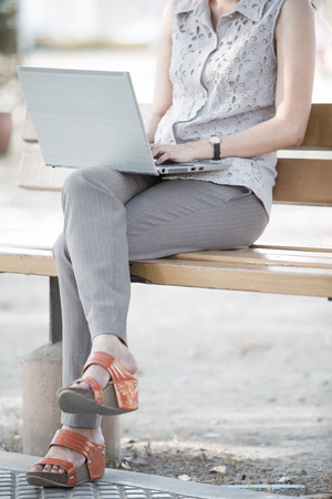 Portrait of a smiling young business woman using laptop on chairの写真素材