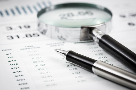 magnifying glass and pen over graph on tableの写真素材