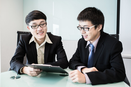 Two managers discussing contract in meeting room.Asianの写真素材