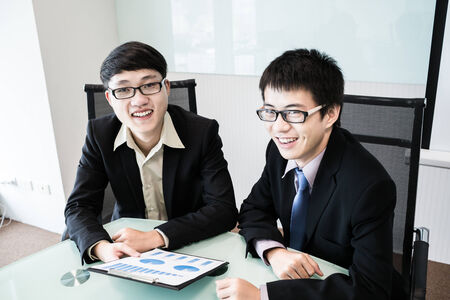 Two managers discussing contract in meeting room.Asianの写真素材