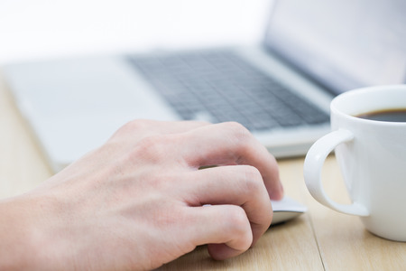 Hands of a man working with laptop and cup of coffeeの写真素材