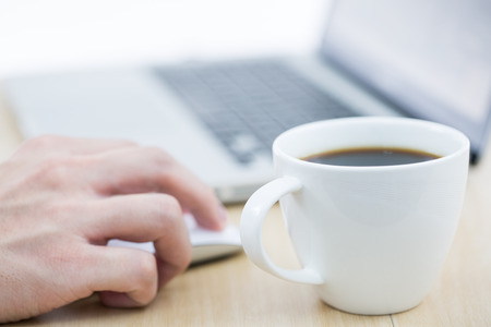 Hands of a man working with laptop and cup of coffeeの写真素材