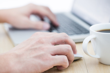 Hands of a man working with laptop and cup of coffeeの写真素材