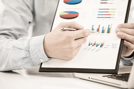 Businessman analyzing investment charts with laptop. の写真素材