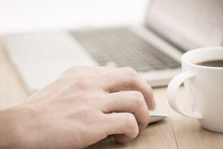 Hands of a man working with laptop and cup of coffeeの写真素材
