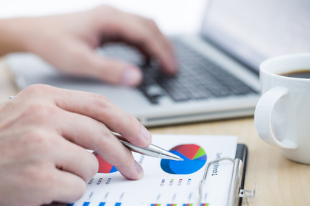 Businessman analyzing investment charts with laptop. の写真素材