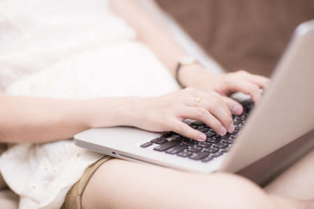 happy brunette woman with a laptop in the bed at homeの写真素材