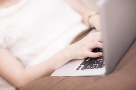 happy brunette woman with a laptop in the bed at homeの写真素材