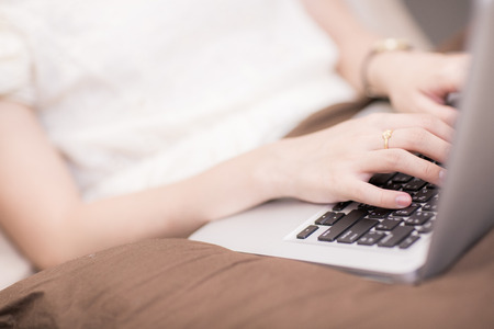 happy brunette woman with a laptop in the bed at homeの写真素材