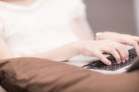 happy brunette woman with a laptop in the bed at homeの写真素材
