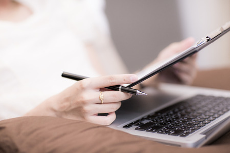 Beautiful woman working at home with laptop in bedの写真素材