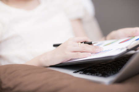 Beautiful woman working at home with laptop in bedの写真素材