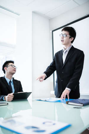 Businessman standing in front of colleagues during a meeting.Asianの写真素材
