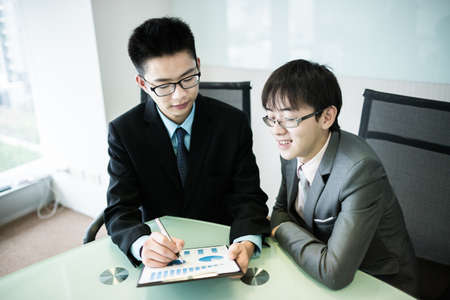 Two managers discussing contract in meeting room.Asianの写真素材