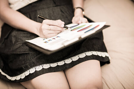 Beautiful woman working at home with report on bedの写真素材