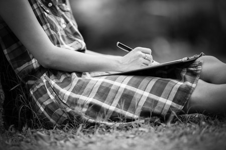 Young business woman planing, writing and reviewing report at city park.の写真素材