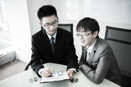 Two managers discussing contract in meeting room.Asianの写真素材